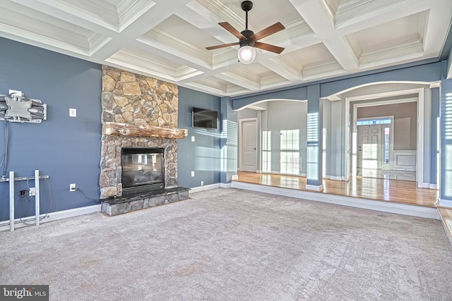 unfurnished living room featuring coffered ceiling, carpet flooring, ornamental molding, a fireplace, and beamed ceiling