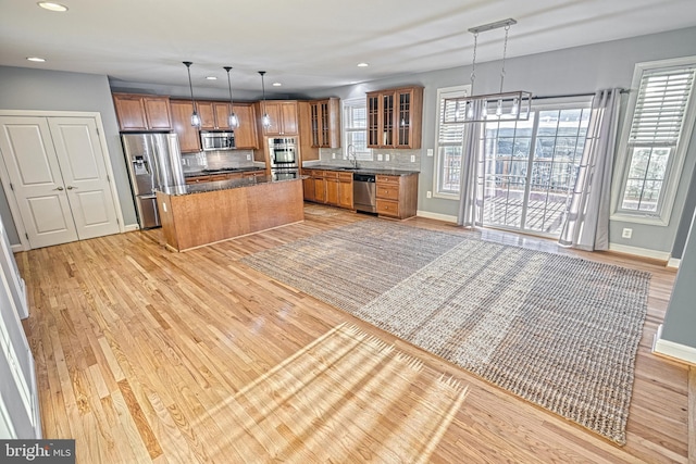 kitchen with a center island, light hardwood / wood-style flooring, tasteful backsplash, decorative light fixtures, and stainless steel appliances