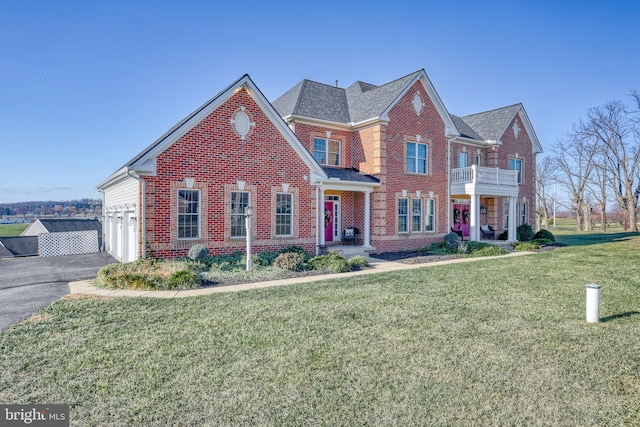 view of front of home featuring a balcony, a front lawn, and a garage