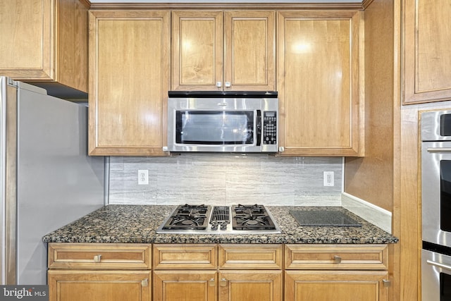 kitchen featuring dark stone countertops, decorative backsplash, and appliances with stainless steel finishes