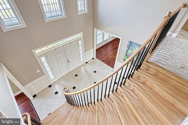 foyer entrance with a healthy amount of sunlight, wood-type flooring, and a towering ceiling