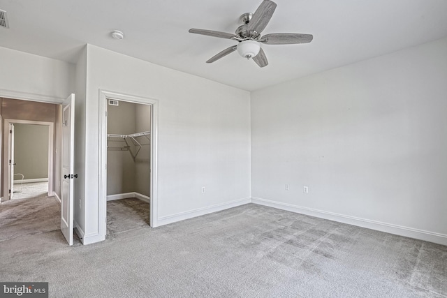 unfurnished bedroom with ceiling fan, a walk in closet, light carpet, and a closet