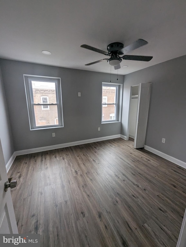 unfurnished bedroom with ceiling fan and dark wood-type flooring