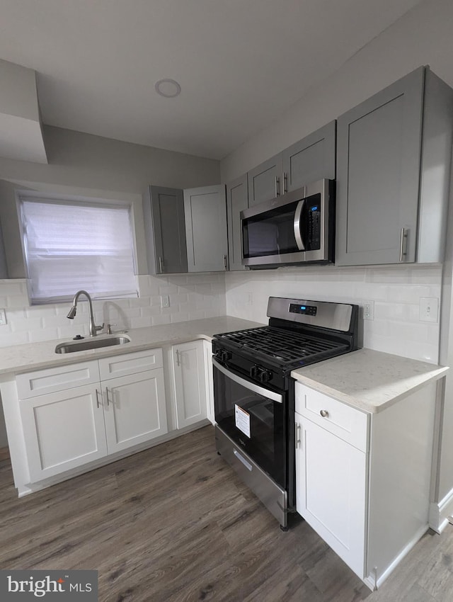 kitchen with dark hardwood / wood-style flooring, decorative backsplash, sink, and stainless steel appliances