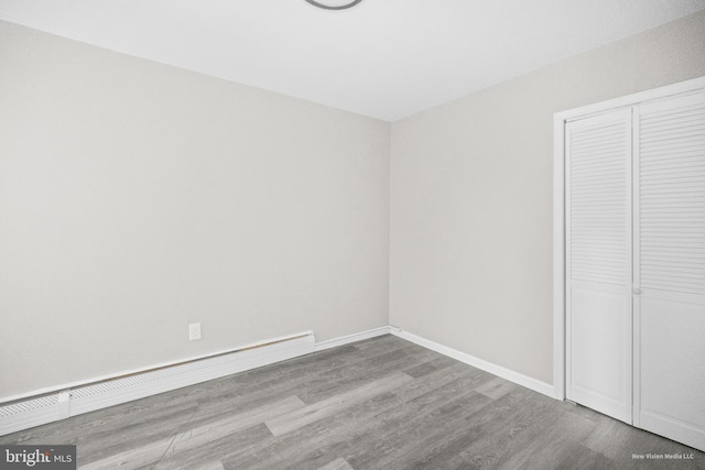 unfurnished bedroom featuring a baseboard radiator, a closet, and light hardwood / wood-style floors