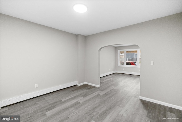 unfurnished room featuring hardwood / wood-style flooring and a baseboard radiator