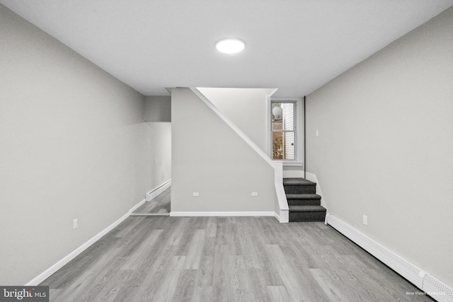 basement with light wood-type flooring and a baseboard radiator