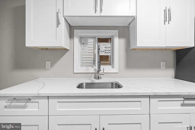 kitchen featuring light stone countertops, sink, and white cabinets