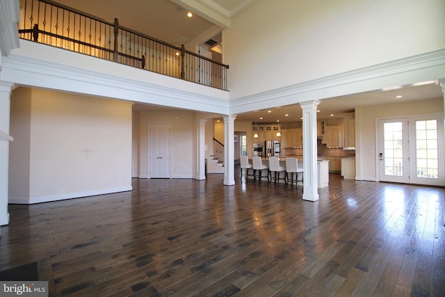 unfurnished living room featuring a high ceiling and dark wood-type flooring