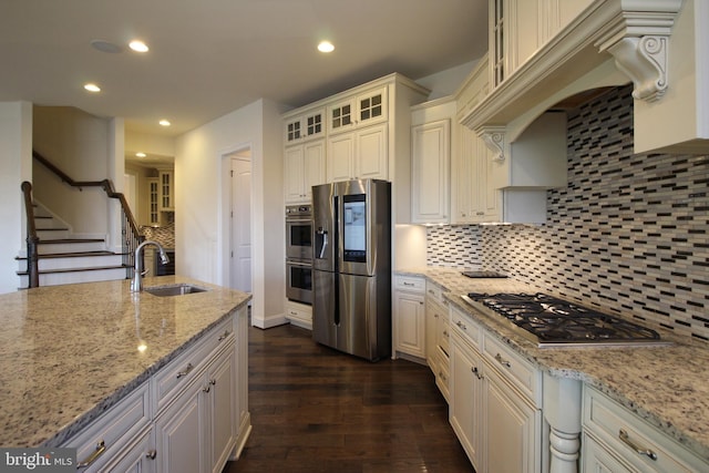 kitchen with light stone counters, sink, stainless steel appliances, and tasteful backsplash