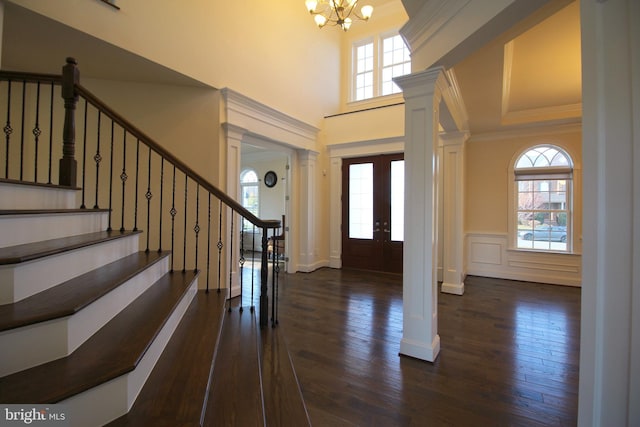 foyer with a raised ceiling, french doors, dark wood-type flooring, and a notable chandelier