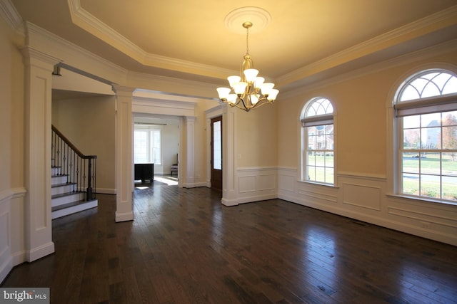 unfurnished dining area featuring ornamental molding, dark hardwood / wood-style flooring, a tray ceiling, and a notable chandelier