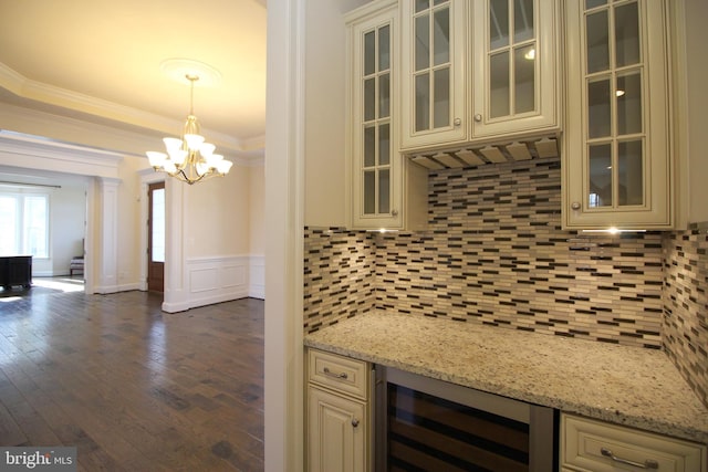 kitchen with cream cabinets, light stone countertops, hanging light fixtures, and beverage cooler