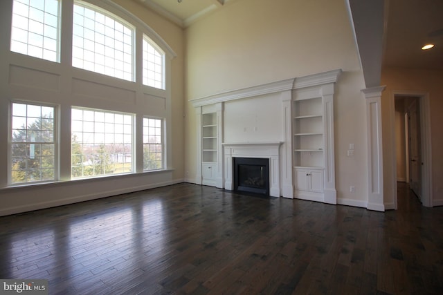 unfurnished living room featuring a towering ceiling and dark wood-type flooring