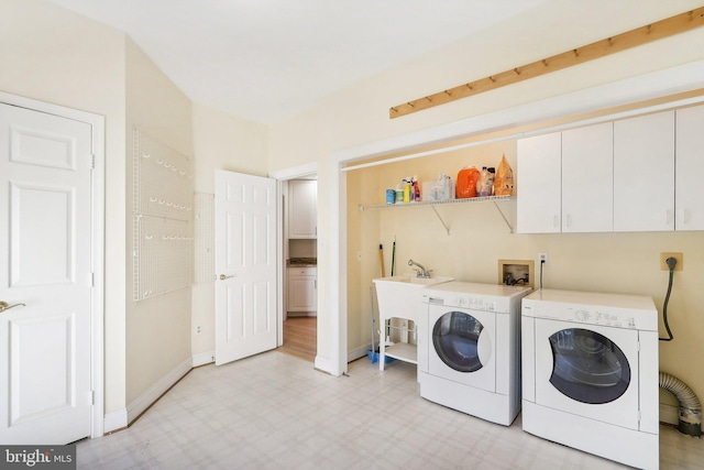 clothes washing area with cabinets and washing machine and clothes dryer