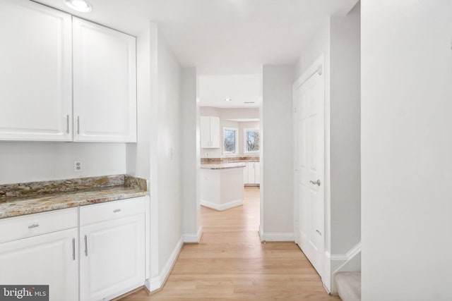 interior space featuring white cabinets, light hardwood / wood-style floors, and stone counters