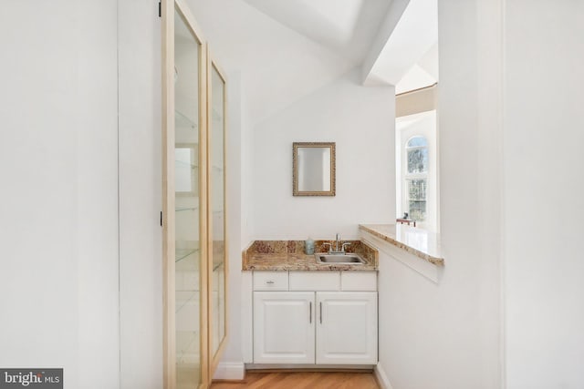 bathroom with hardwood / wood-style flooring, vanity, and vaulted ceiling