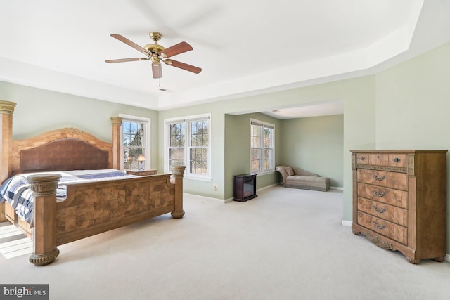 bedroom featuring ceiling fan, light carpet, and a tray ceiling