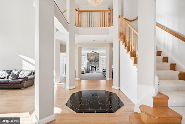 foyer featuring hardwood / wood-style flooring, a towering ceiling, and a fireplace