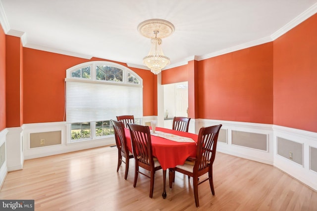 dining space featuring light hardwood / wood-style floors, an inviting chandelier, and ornamental molding