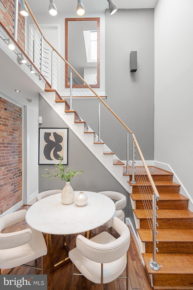 interior space with hardwood / wood-style floors, a skylight, a high ceiling, and brick wall