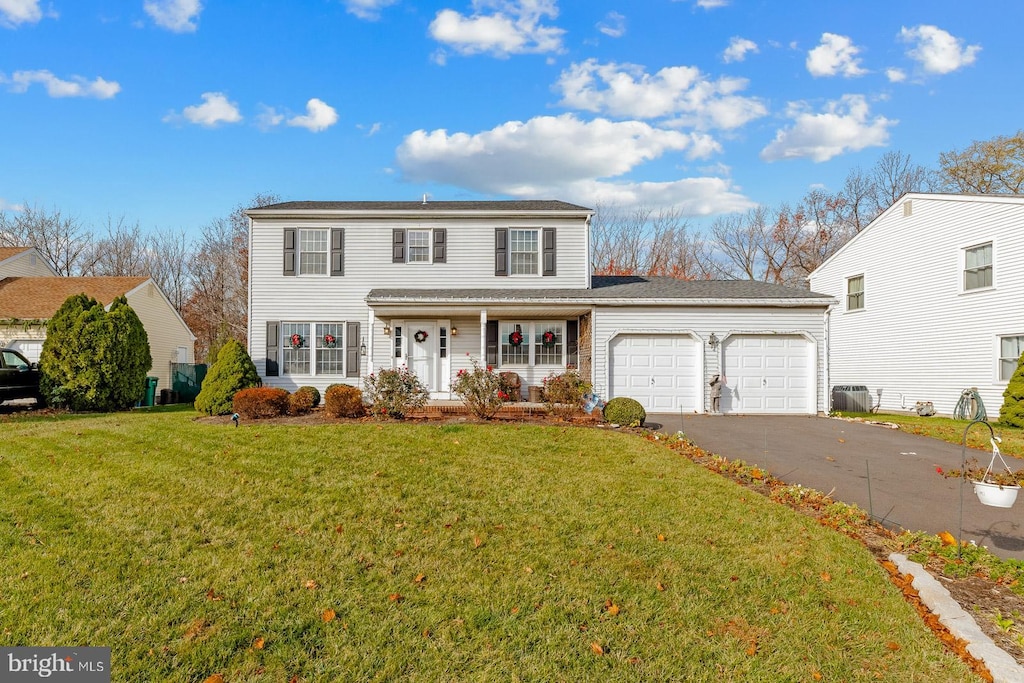 view of property featuring covered porch, a garage, and a front yard