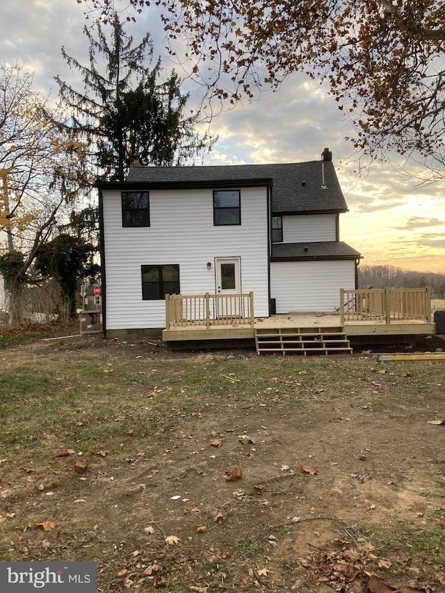 back house at dusk featuring a wooden deck