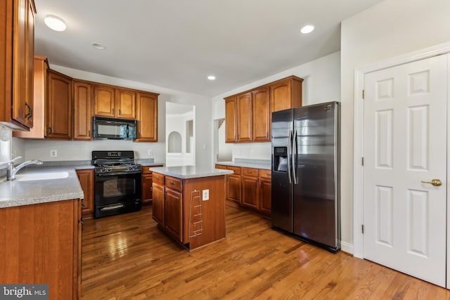 kitchen featuring black appliances, dark hardwood / wood-style floors, a kitchen island, and sink