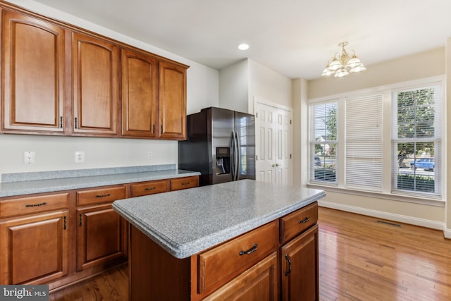 kitchen featuring an inviting chandelier, stainless steel refrigerator with ice dispenser, hardwood / wood-style flooring, decorative light fixtures, and a kitchen island