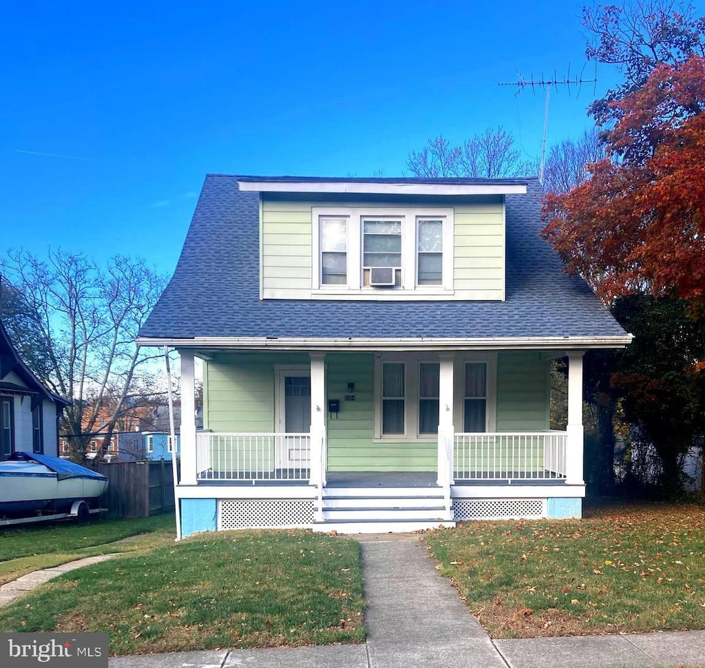 bungalow-style house featuring cooling unit, a front lawn, and covered porch