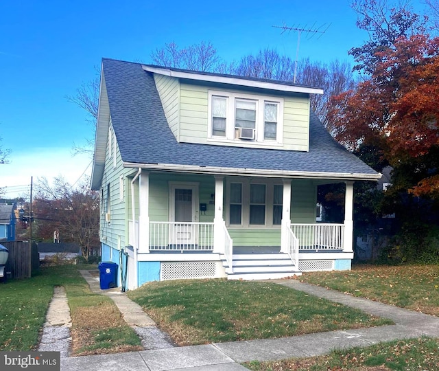 view of front of home with cooling unit, covered porch, and a front yard