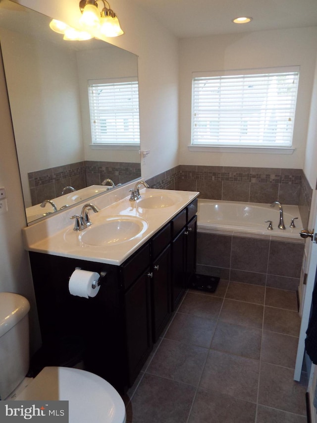 bathroom featuring tiled tub, plenty of natural light, tile patterned floors, and toilet