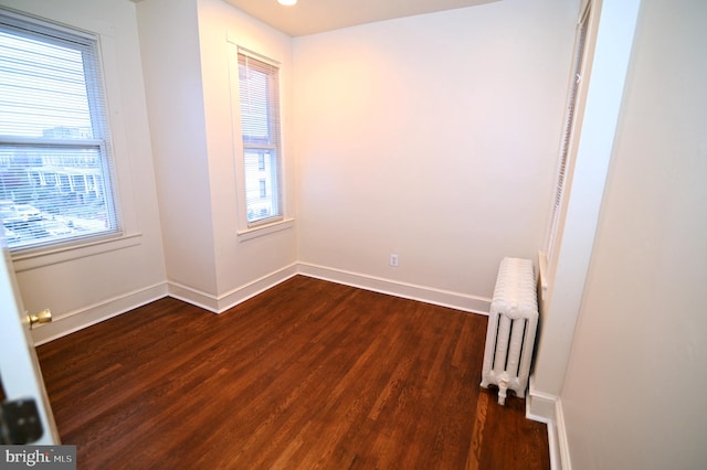 empty room featuring radiator heating unit and dark wood-type flooring