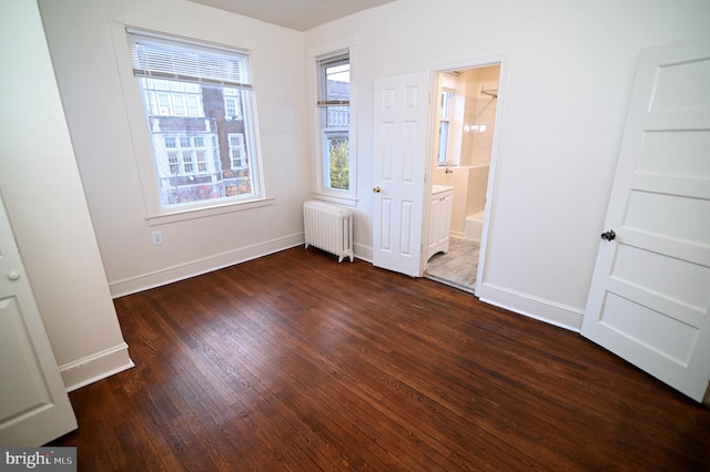 unfurnished bedroom with ensuite bathroom, radiator heating unit, and dark wood-type flooring