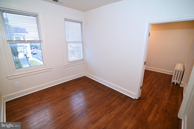 empty room with radiator heating unit and dark wood-type flooring