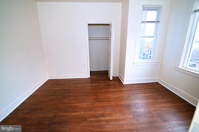 unfurnished bedroom with dark hardwood / wood-style floors and a closet