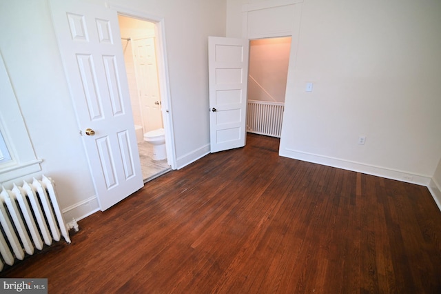 unfurnished bedroom featuring radiator heating unit and dark hardwood / wood-style floors