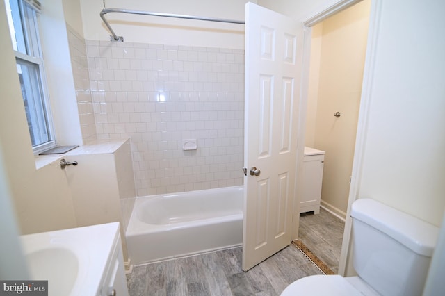 full bathroom featuring vanity, wood-type flooring, tiled shower / bath combo, and toilet