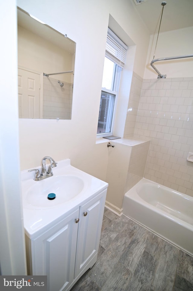 bathroom featuring hardwood / wood-style floors, tiled shower / bath combo, and vanity