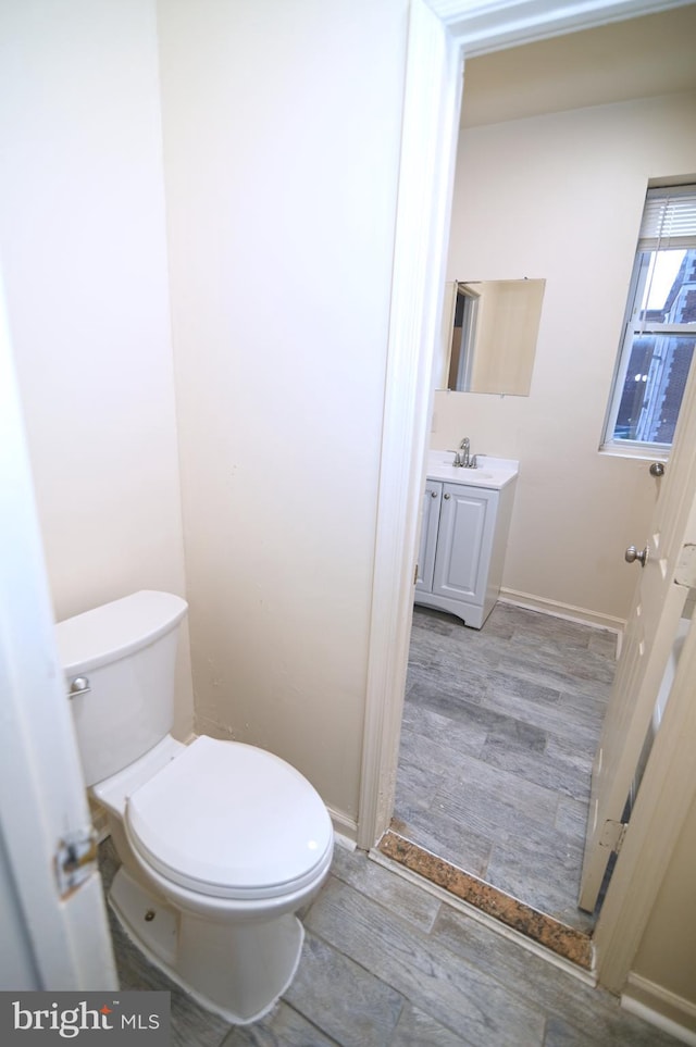 bathroom with wood-type flooring, vanity, and toilet