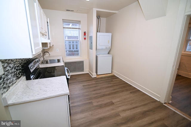 kitchen featuring stainless steel electric range oven, dark wood-type flooring, sink, white cabinetry, and stacked washer / drying machine