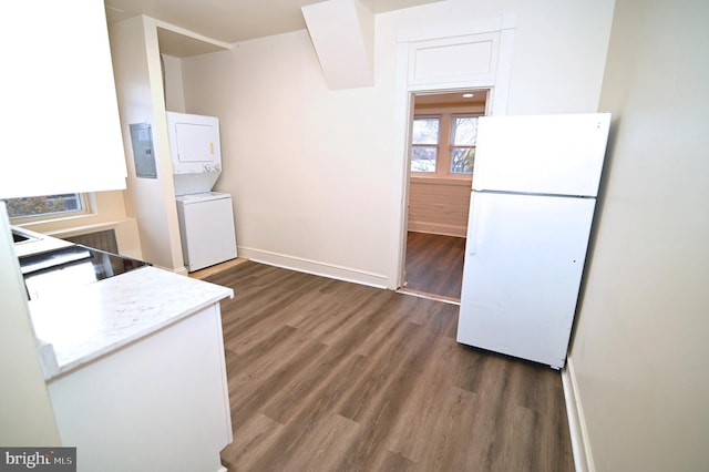 kitchen with white refrigerator, dark hardwood / wood-style floors, and stacked washer / dryer