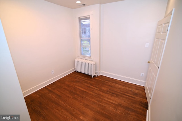 spare room with radiator heating unit and dark hardwood / wood-style floors