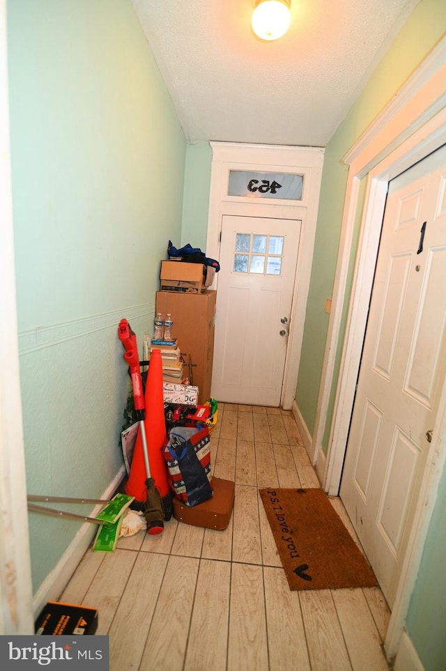 doorway featuring a textured ceiling and light wood-type flooring