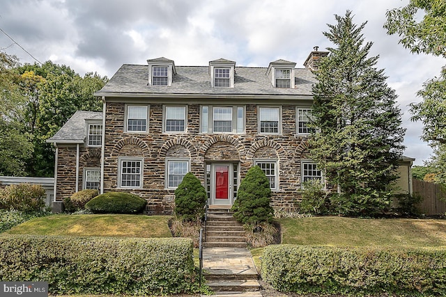 view of front of property with a front yard, stone siding, and a chimney