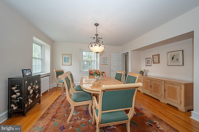 dining area with baseboards, light wood-style flooring, and radiator heating unit