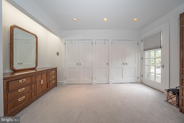 bedroom featuring access to exterior, recessed lighting, light colored carpet, and two closets