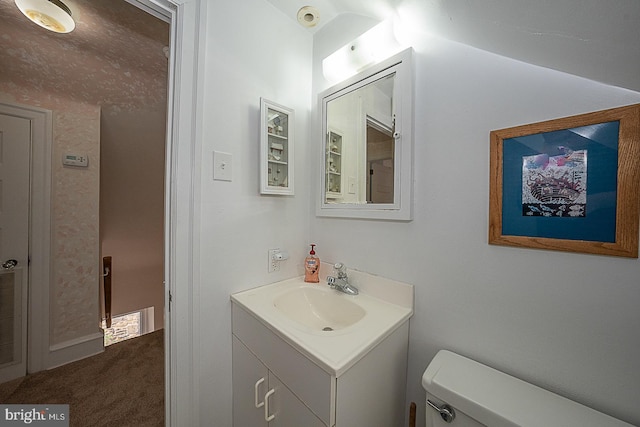 bathroom featuring toilet, vaulted ceiling, and vanity