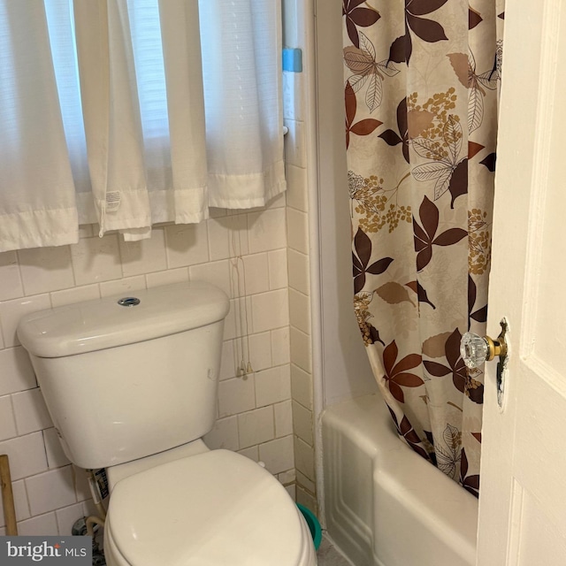 bathroom with shower / tub combo, toilet, and tile walls