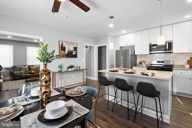 kitchen featuring dark hardwood / wood-style flooring, white cabinetry, pendant lighting, and stainless steel appliances